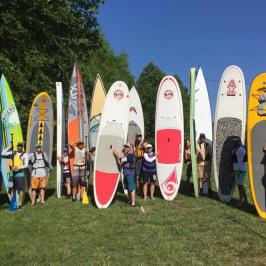 a group of people standing on top of a surfboard