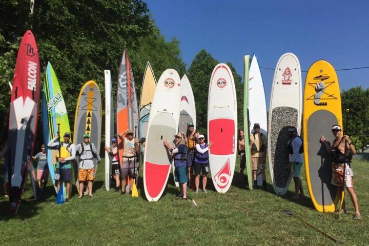 a group of people standing on top of a surfboard